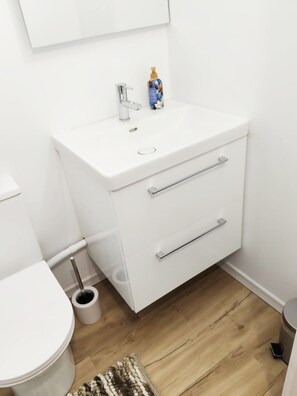Ein helles Badezimmer mit Waschbecken, zwei Schubladen, Toilette und Bidet.