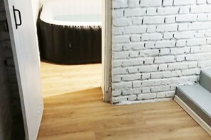 Ein Zimmer mit weiß verputzter Wand, Holzboden und einem schwarzen, runden Gegenstand auf einem Tisch.