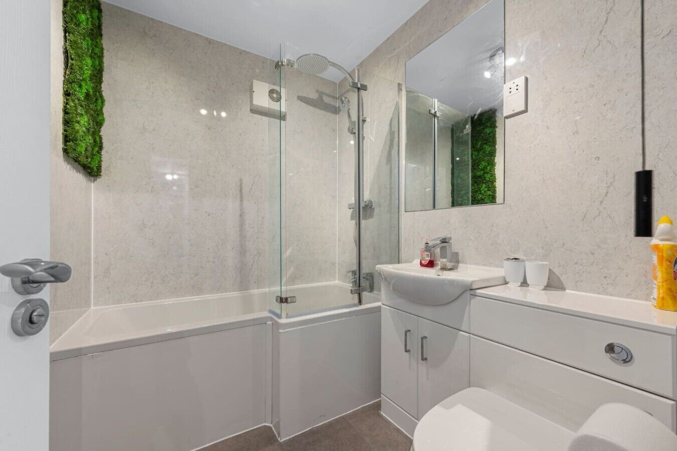 Une salle de bain moderne avec une douche à parois de verre, un lavabo blanc avec un miroir et des toilettes.