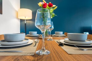 Ein Esstisch mit Tellern, Besteck, einem Weinglas und einer Blumenvase.