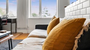 Una sala de estar moderna con un sofá, una mesa de centro y vistas al exterior a través de amplios ventanales.