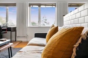 Ein modernes Wohnzimmer mit einer Couch, einem Couchtisch und Blick ins Freie durch große Fenster.