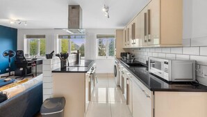 Una cocina moderna con una isla central, electrodomésticos integrados y grandes ventanales con vistas.