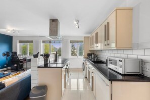 Eine moderne Küche mit einer zentralen Kochinsel, eingebauten Geräten und großen Fenstern mit Blick.