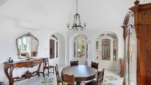 Un comedor con una mesa redonda, sillas, una araña y un espejo grande.