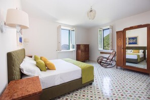 Un dormitorio con cama, una silla, un tocador y un espejo.