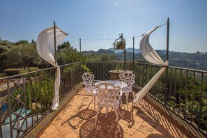 Una terraza con una mesa y sillas, una planta colgante y vistas del paisaje.