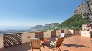Una terraza con vistas a las montañas, una mesa y dos sillas.