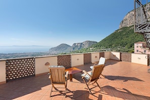 Una terrazza con vista sulle montagne, un tavolo e due sedie.