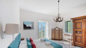 Un dormitorio con cama, ventana, candelabro y armario.