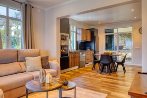A modern living room with a sofa, coffee table, and dining area with chairs and a table. - Freitas Panoramic, a Home in Madeira (Ponta do Sol)