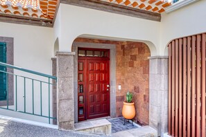 A red door with a stone archway, a potted plant, and a metal railing. - Freitas Panoramic, a Home in Madeira (Ponta do Sol)
