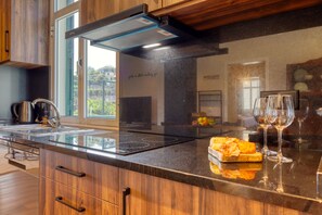 A modern kitchen with a built-in stove, a window, and a countertop with a glass top. - Freitas Panoramic, a Home in Madeira (Ponta do Sol)