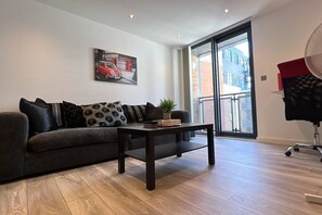 Ein modernes Wohnzimmer mit einer Couch, einem Couchtisch und einem Gemälde, das ein Auto und eine Telefonzelle zeigt.