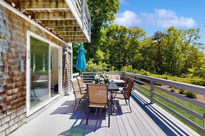 An outdoor deck with a table and chairs, a blue umbrella, and a white railing. - Bright Falmouth Home With Open Layout, AC & Deck (Falmouth)