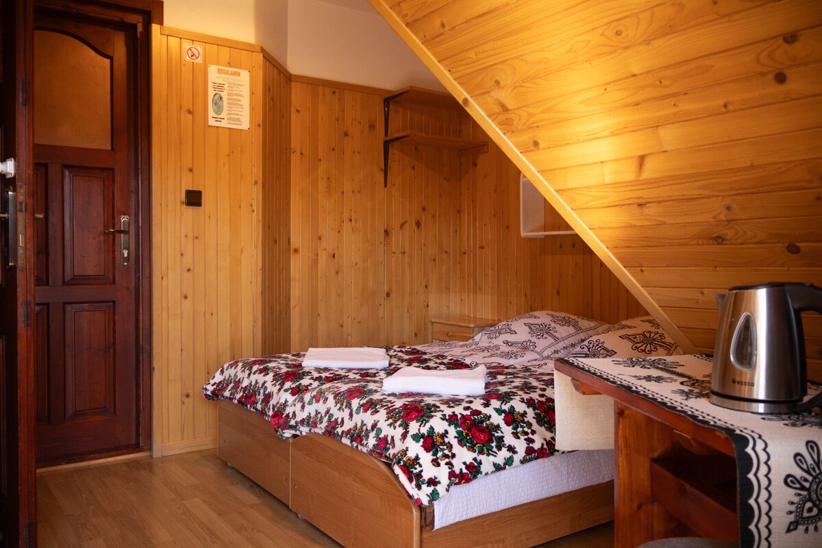 Una habitación de madera con una cama, una puerta de madera y un letrero colgado en la pared.
