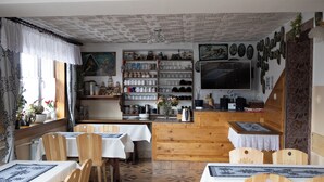 Un coin repas avec des chaises et des tables en bois, un comptoir de cuisine et un téléviseur fixé au mur.