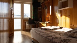 Une pièce en bois avec un lit, une chaise, un radiateur et une fenêtre.