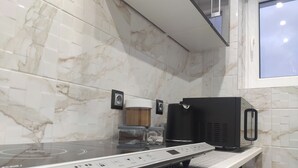 A kitchen with a modern induction cooktop, a coffee machine, and a microwave.