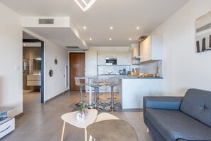 Et moderne køkken med en central ø, barstole og et spiseområde med en sofa og sofabord.
