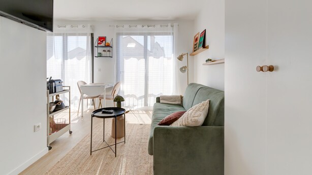 Ett vardagsrum med en soffa, ett soffbord, en tv och en matplats med en stol och ett bord.