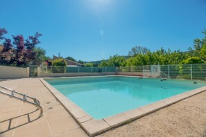 A rectangular swimming pool with a metal ladder on the left, surrounded by a fence and a tiled deck. - Mazet de Soleil - Maisonnette climatisée pour 4 (Saint-Martin-de-Brômes)