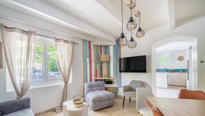 Ein modernes Wohnzimmer mit Sofa, Hocker, Esstisch und Stühlen.