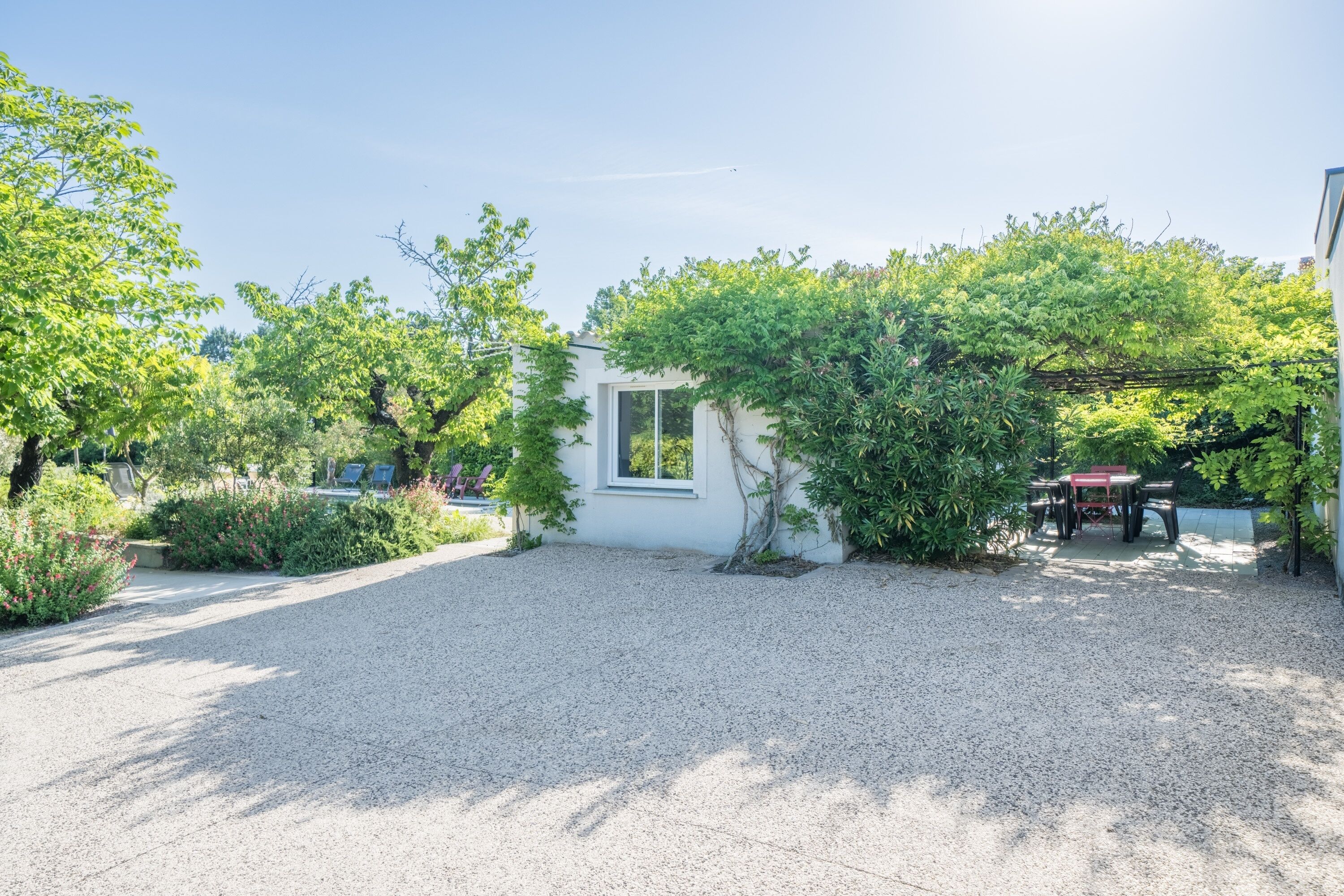 A gravel driveway leading to a white building with a window and a door.