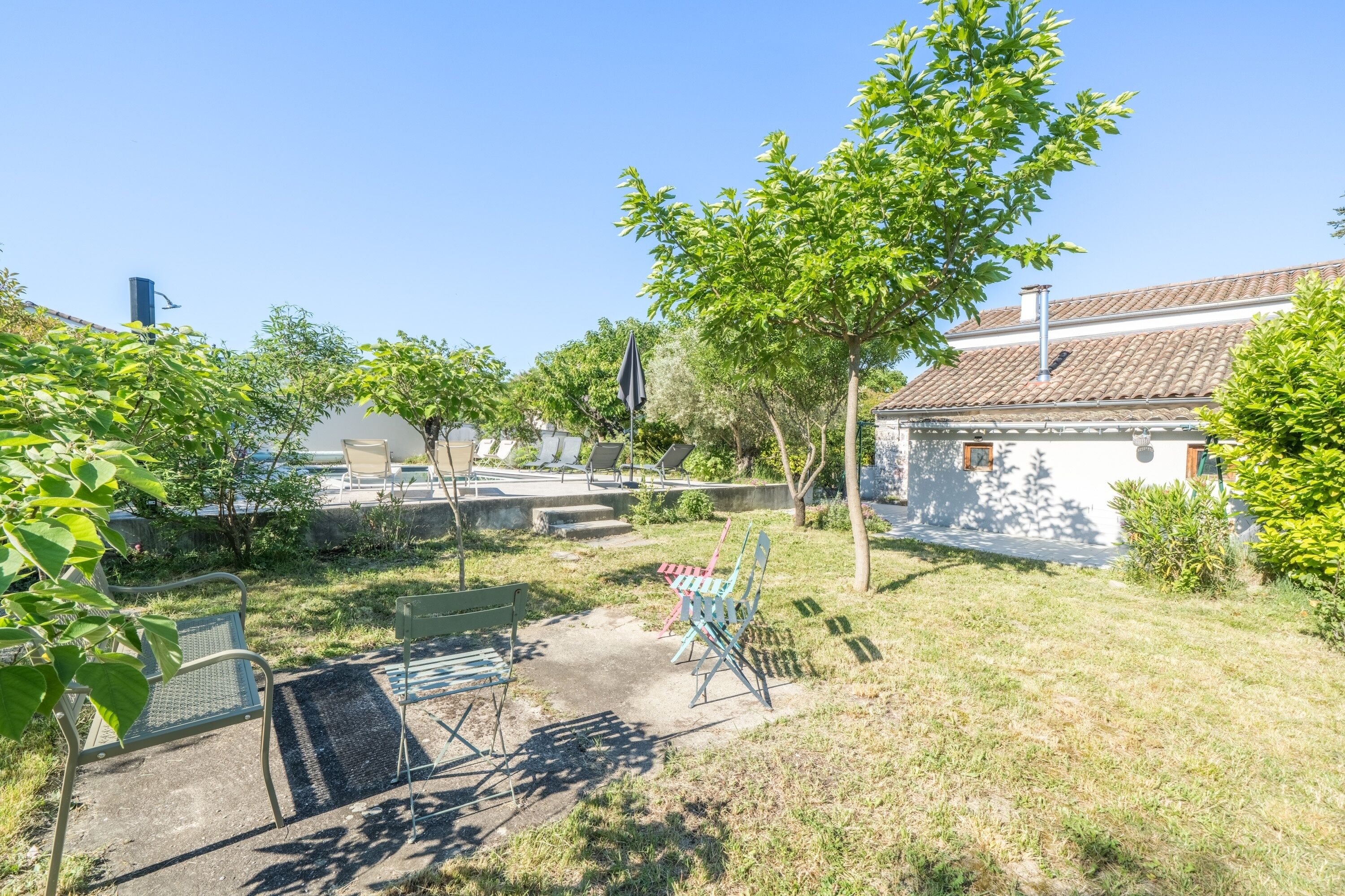 A backyard with a patio, a small garden, and a building with a tiled roof.