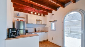 Una cocina moderna con encimera de madera, armarios blancos, microondas integrado y cafetera.