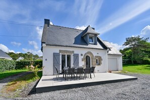 Ein Haus mit überdachter Terrasse, einem steinernen Bogen und einem kleinen Anbau.