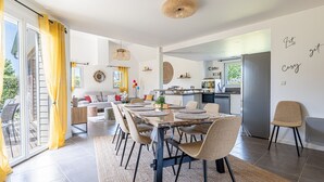 Eine moderne Küche mit Kühlschrank, Herd und Essbereich mit Tisch und Stühlen.