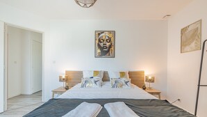 Ein Schlafzimmer mit einem Bett, zwei Nachttischen, einem Wandbild und einer Tür.