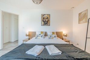 A bedroom with a bed, two bedside tables, a wall art piece, and a door. - Normandie Escape House - À 5 min des plages (Manvieux)
