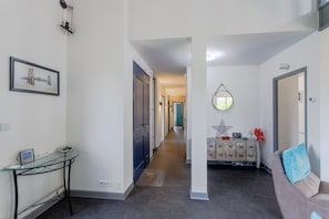 A hallway with a glass table, a sofa, and a dresser with decorative items.