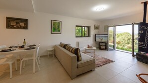 Uma sala de estar moderna com sofá, mesa de jantar, cadeiras, TV e uma grande janela com vista.