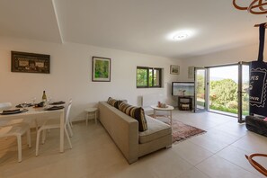 En moderne stue med sofa, spisebord, stole, et fjernsyn og et stort vindue med udsigt.