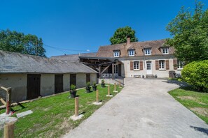 Une cour avec un bâtiment, des plantes en pot et un chemin.