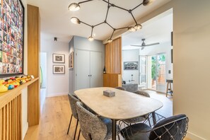 Et moderne spiseområde med et rundt bord, fletstole og en pendel.