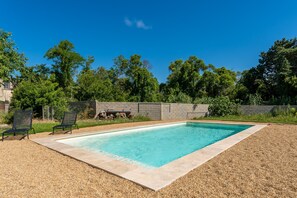 A rectangular swimming pool with a tiled edge, surrounded by a gravel area. - La Villa Sola - Climatisée avec piscine privée (Saint Gilles)