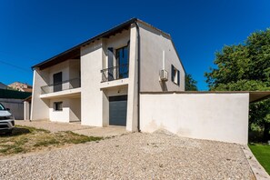A two-story house with a balcony, a garage, and a gravel driveway. - La Villa Sola - Climatisée avec piscine privée (Saint Gilles)