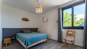 Een slaapkamer met een bed, een stoel, een raam en een decoratie aan de muur.