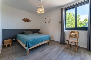 Ein Schlafzimmer mit einem Bett, einem Sessel, einem Fenster und einer Wanddekoration.