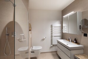 A modern bathroom with a glass shower enclosure, a white toilet, a vanity with a mirror, and a towel rack. - Le Madison - À moins d'1 km de la plage (Pléneuf-Val-André)