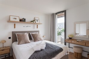 A modern bedroom with a bed, bedside tables, a dresser, a mirror, and a balcony view. - Le Madison - À moins d'1 km de la plage (Pléneuf-Val-André)