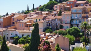 Un quartier résidentiel situé sur une colline, avec des bâtiments aux toits de tuiles rouges, une végétation luxuriante et un ciel dégagé.