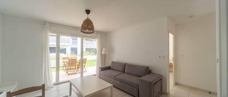 A living room with a sofa, a table, and a hanging light fixture.