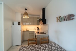 A compact kitchen with a microwave, sink, and wooden chairs. - Le Lavandou Ensoleillé - Bel appt avec terrasse (Le Lavandou)