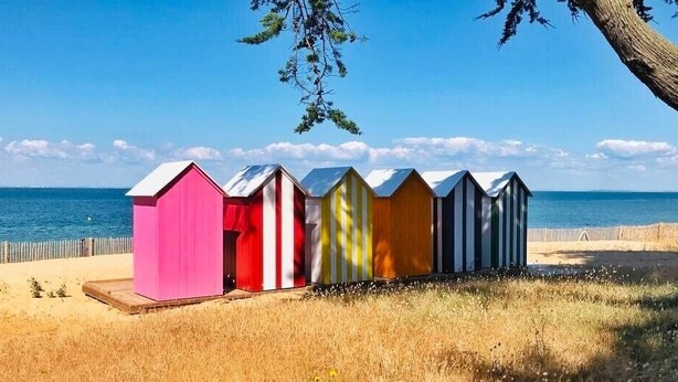 A row of beach huts with a wooden deck and a sandy beach in the background. - Le Temps des Vacances - À 500 m de la plage (La Brée-les-Bains)