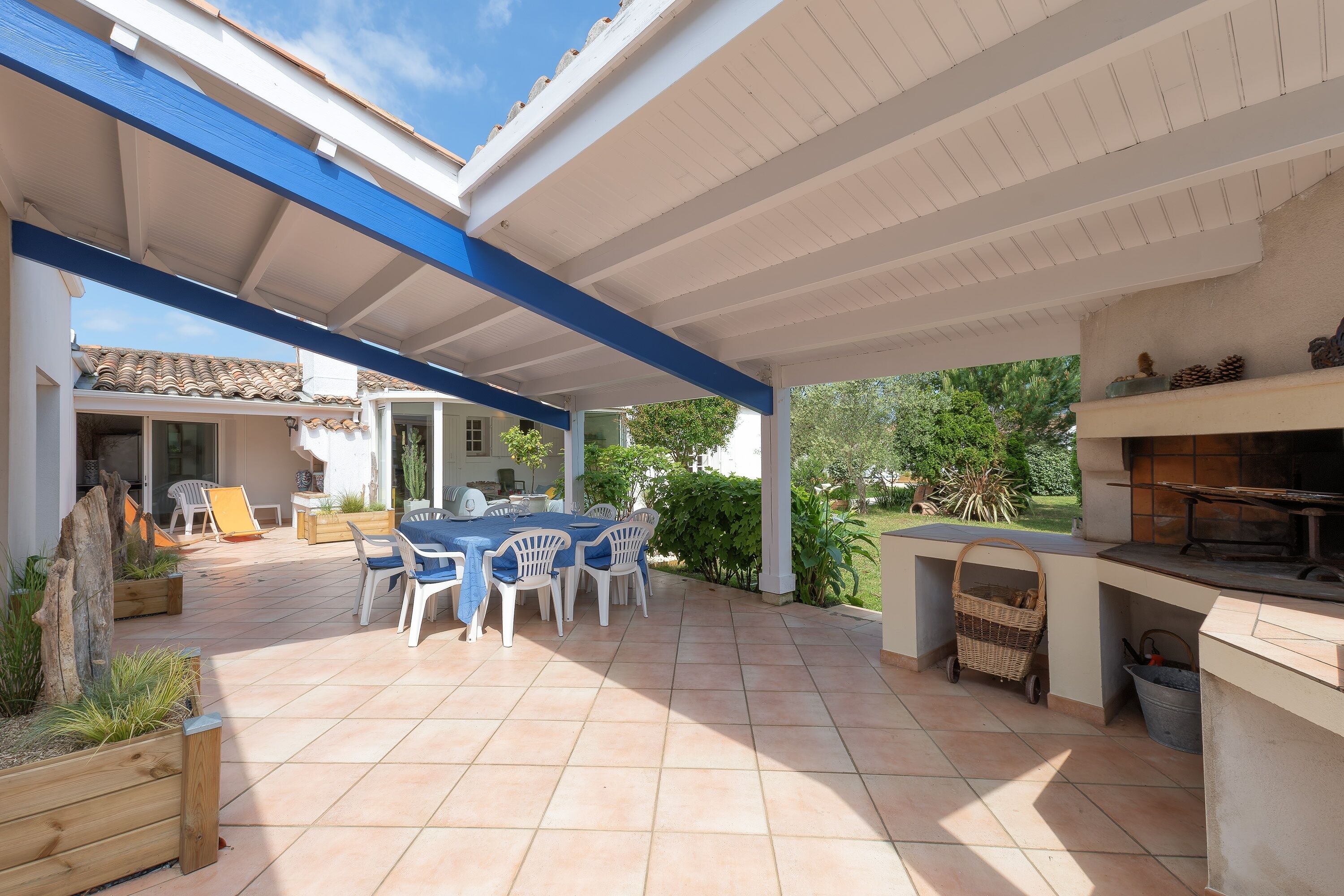 An outdoor patio with a table and chairs, a grill, and a covered area with a tiled floor.